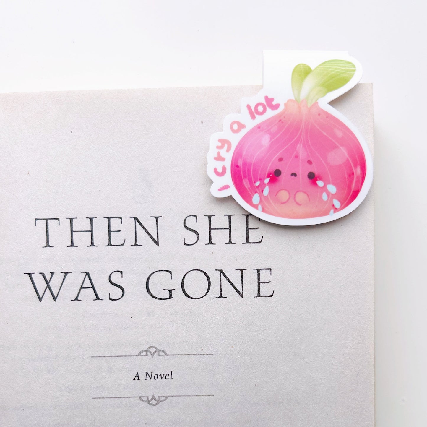 I cry a lot magnetic bookmark clipped on a book titled 'Then She Was Gone' by Lisa Jewell with a decorative sticker on a white background