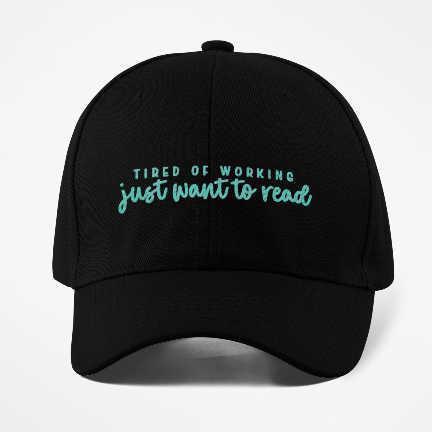 Black cap with teal text 'Tired of working just want to read' on a white background