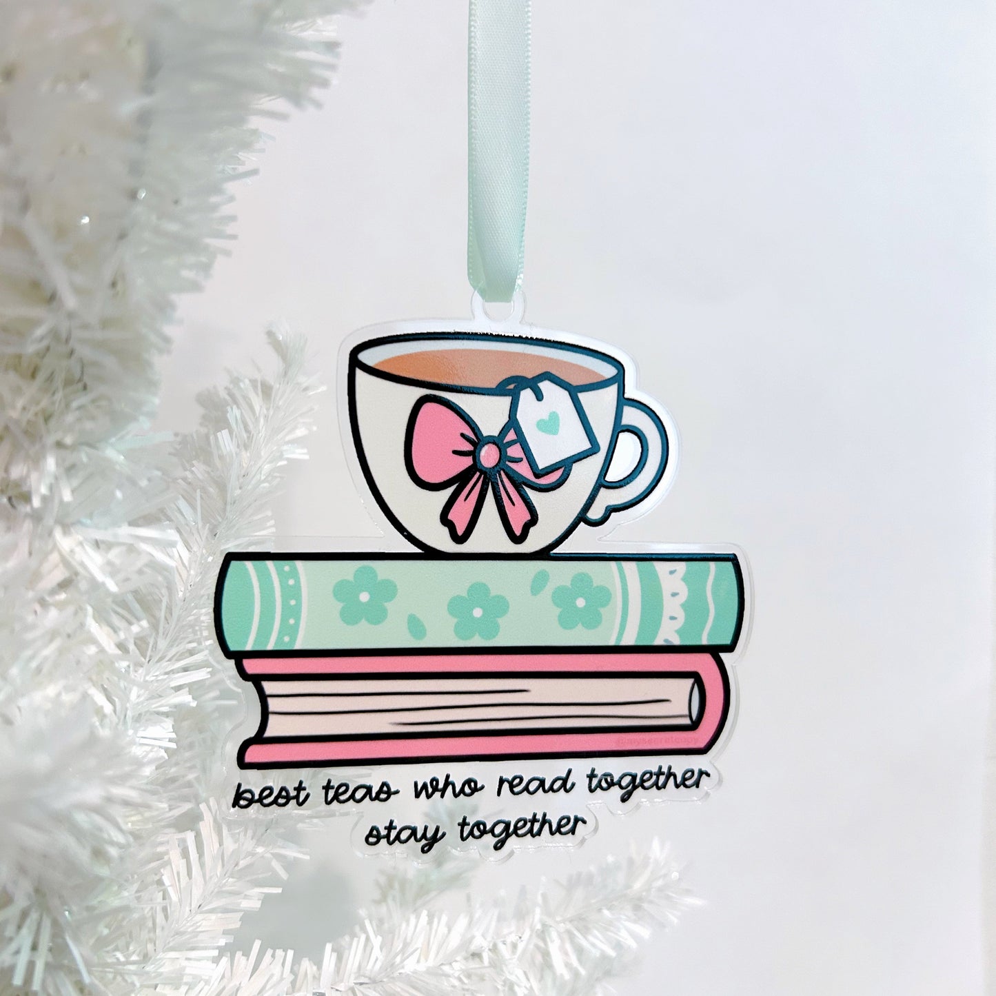 Decorative ornament with a teacup, books on top of a stack of books with the text "best teas who read together stay together" under the books