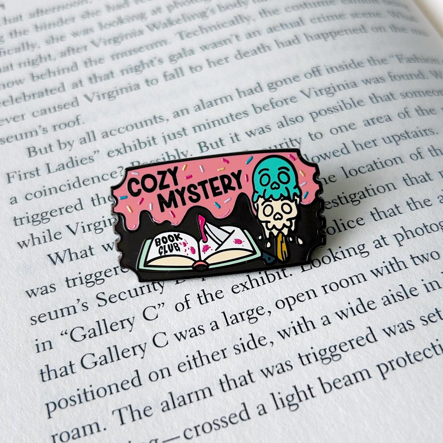 cozy mystery enamel pin on an open book