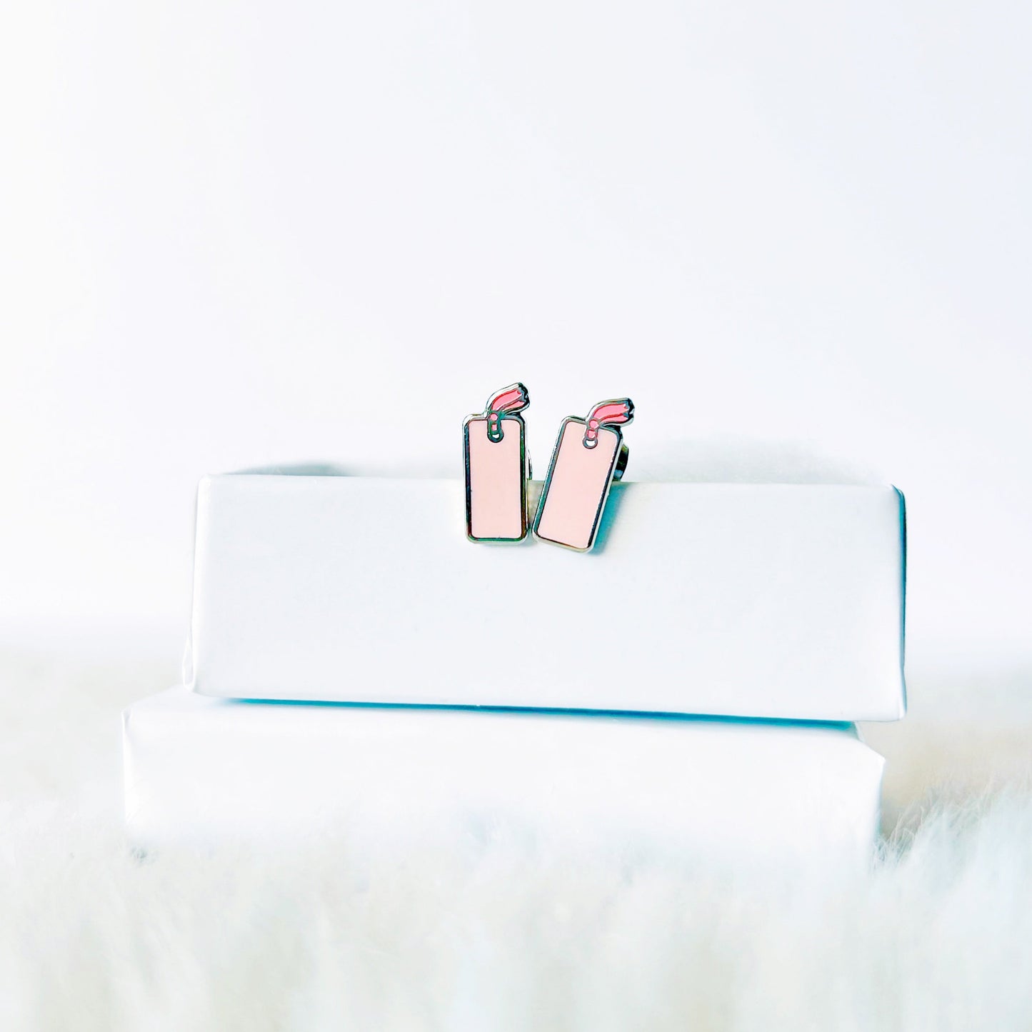 Pink earrings on a white surface with a blurred background