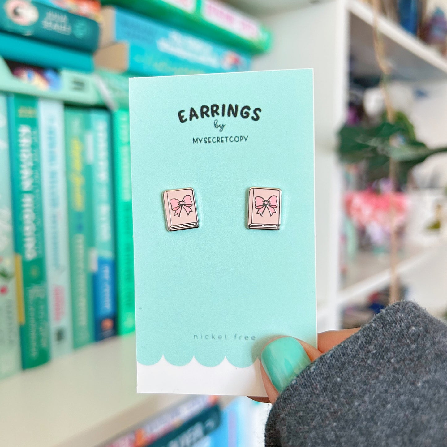 Earrings on a card held in front of a bookshelf