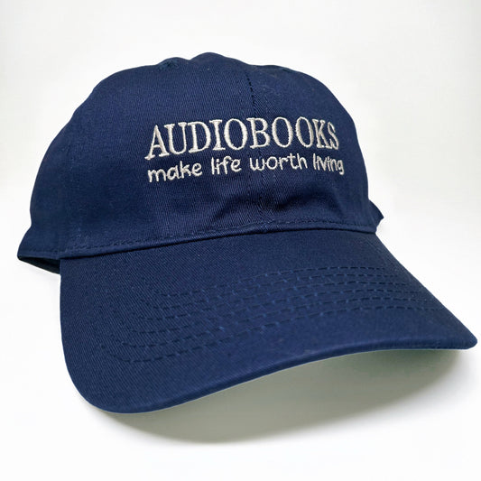 A navy blue baseball cap with white embroidered text reading 'AUDIOBOOKS make life worth living' on the front, shown against a plain white background.