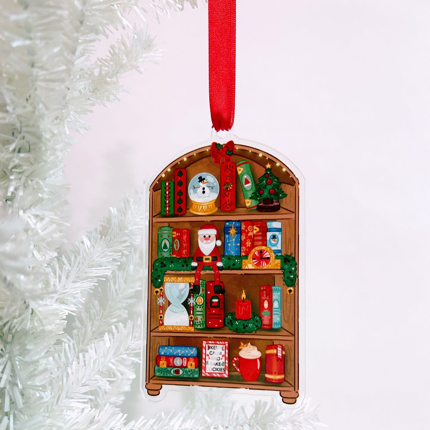 Christmas ornament shaped like a bookshelf with various miniature figurines on a white background