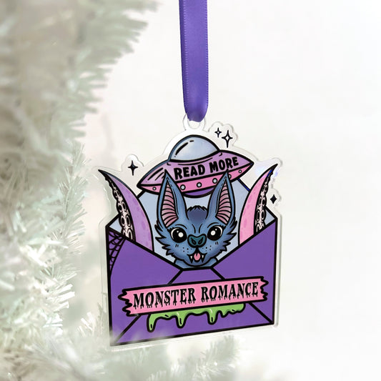 Decorative ornament with a cute monster design and text 'Read More Monster Romance' on a white background.