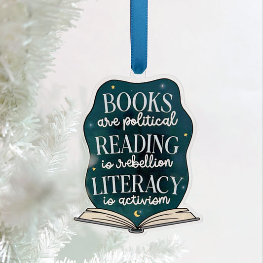 Decorative ornament with  the text that reads "books are political, reading is rebellion, literacy is activism" on a white christmas tree