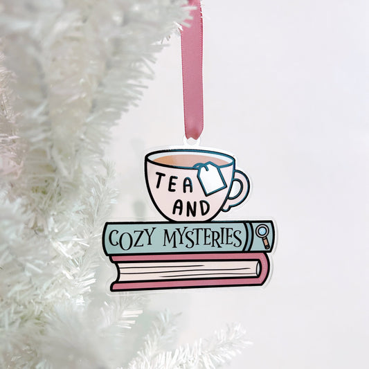 Decorative ornament with a tea cup a book titled cozy mysteries on a white background