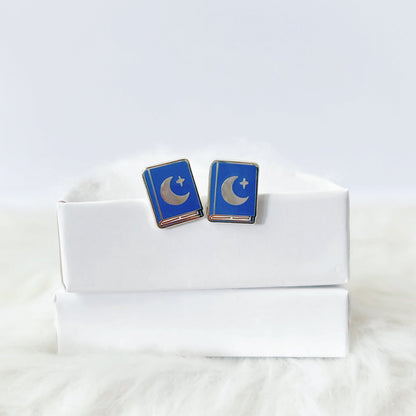 Blue and silver earrings on a white box with a white fur background