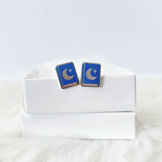 Blue and silver earrings on a white box with a white fur background