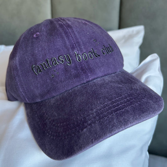 Purple cap with 'Fantasy book club' text on a white pillow
