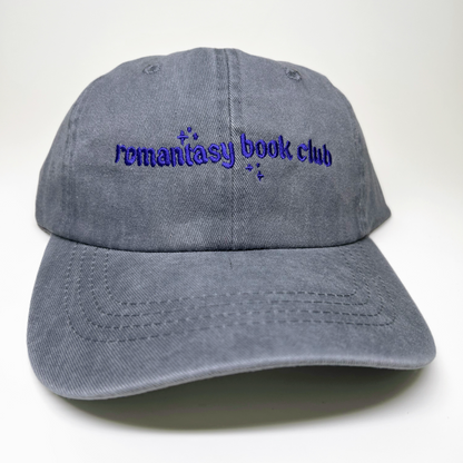 A gray washed cotton baseball cap with 'remantasy book club' embroidered in purple on the front, shown against a plain white background.