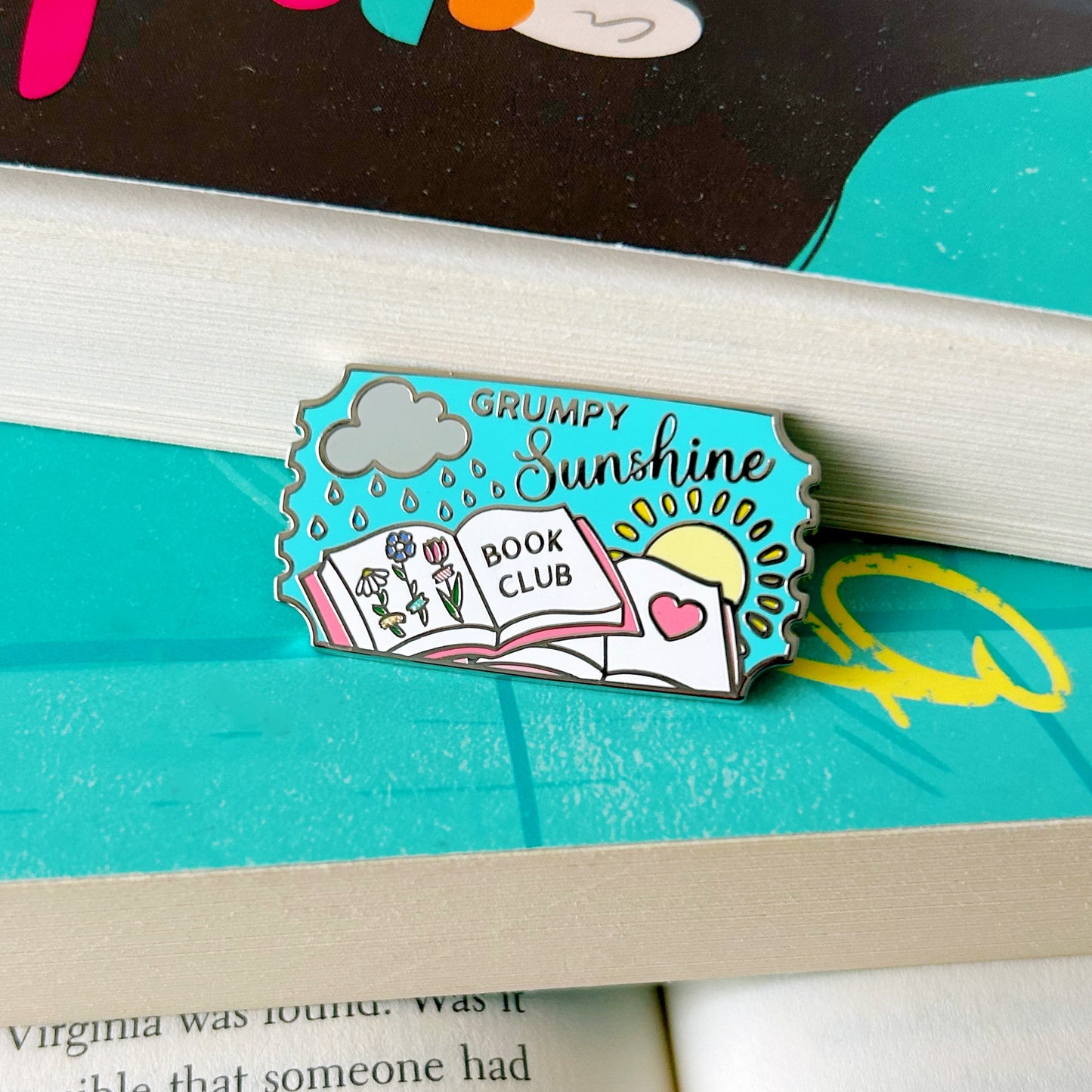 grumpy sunshine enamel pin on a book with a visible text background