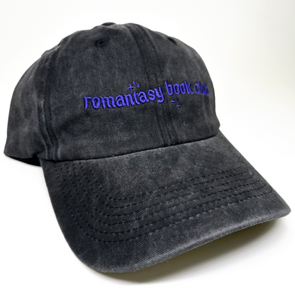A  baseball cap with purple embroidered text reading 'romantasy book club' on the front, shown against a plain white background.
