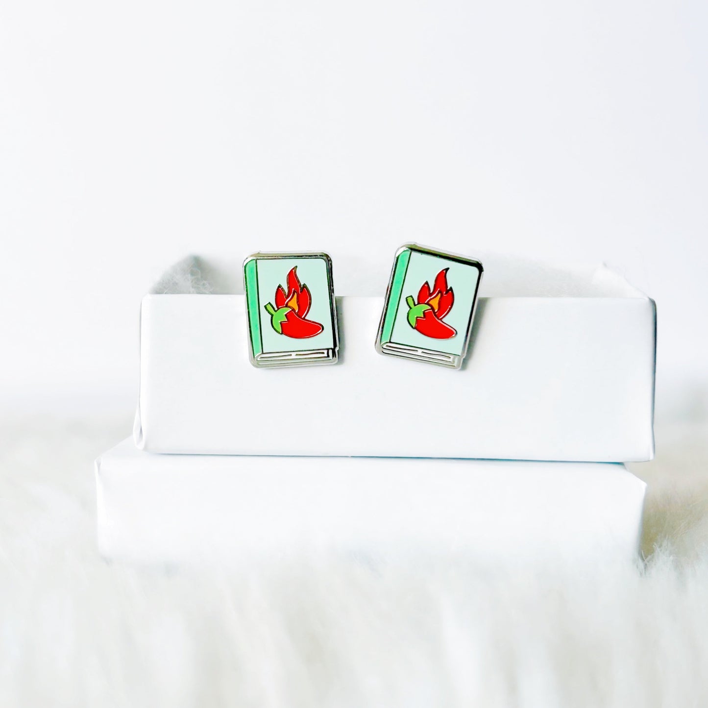 Pair of earrings with red and green design on a white box against a white background