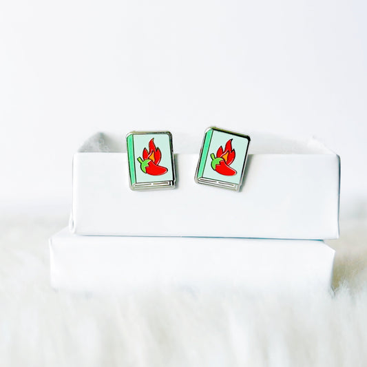 Pair of earrings with red and green design on a white box against a white background