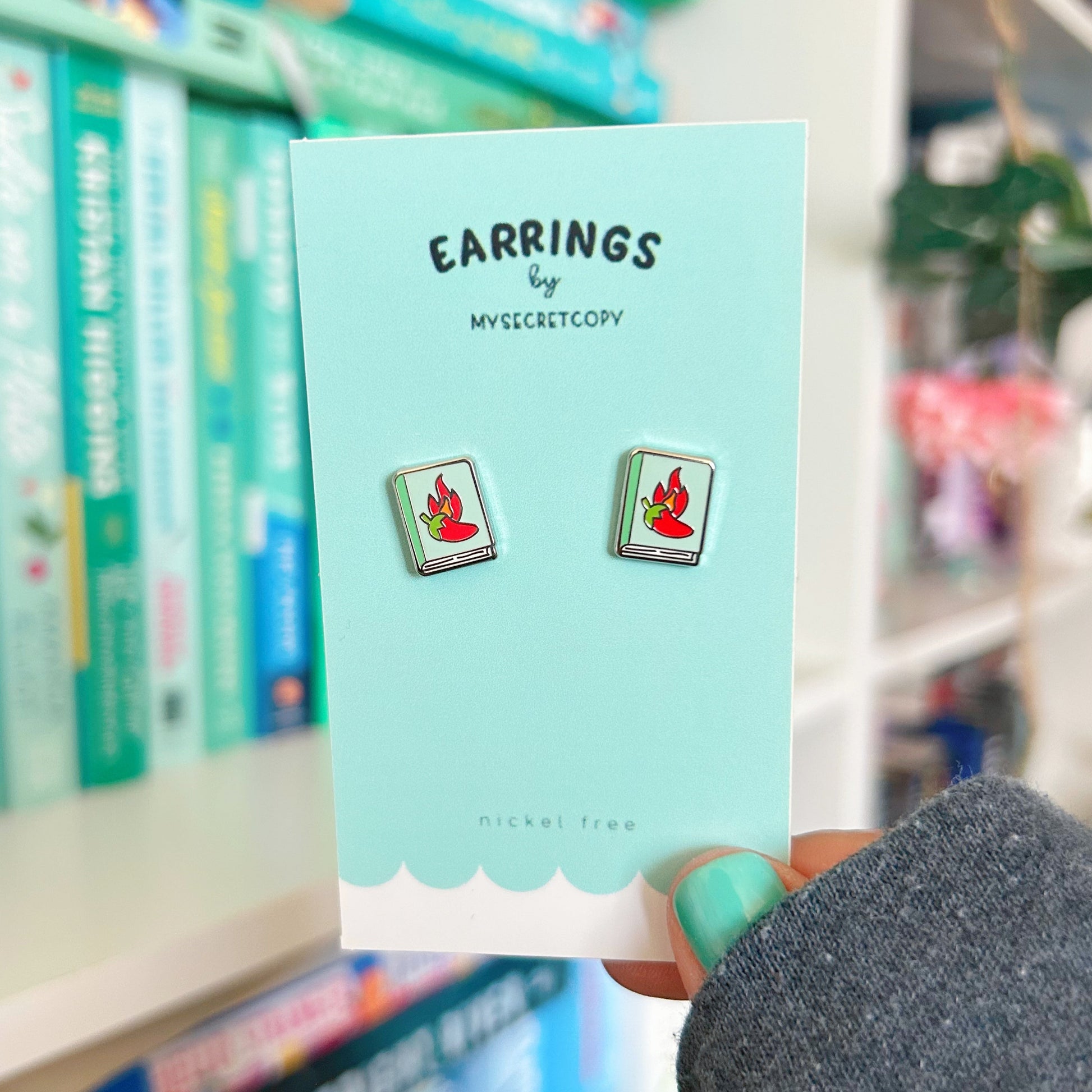 Earring card with earrings on a blurred bookshelf background