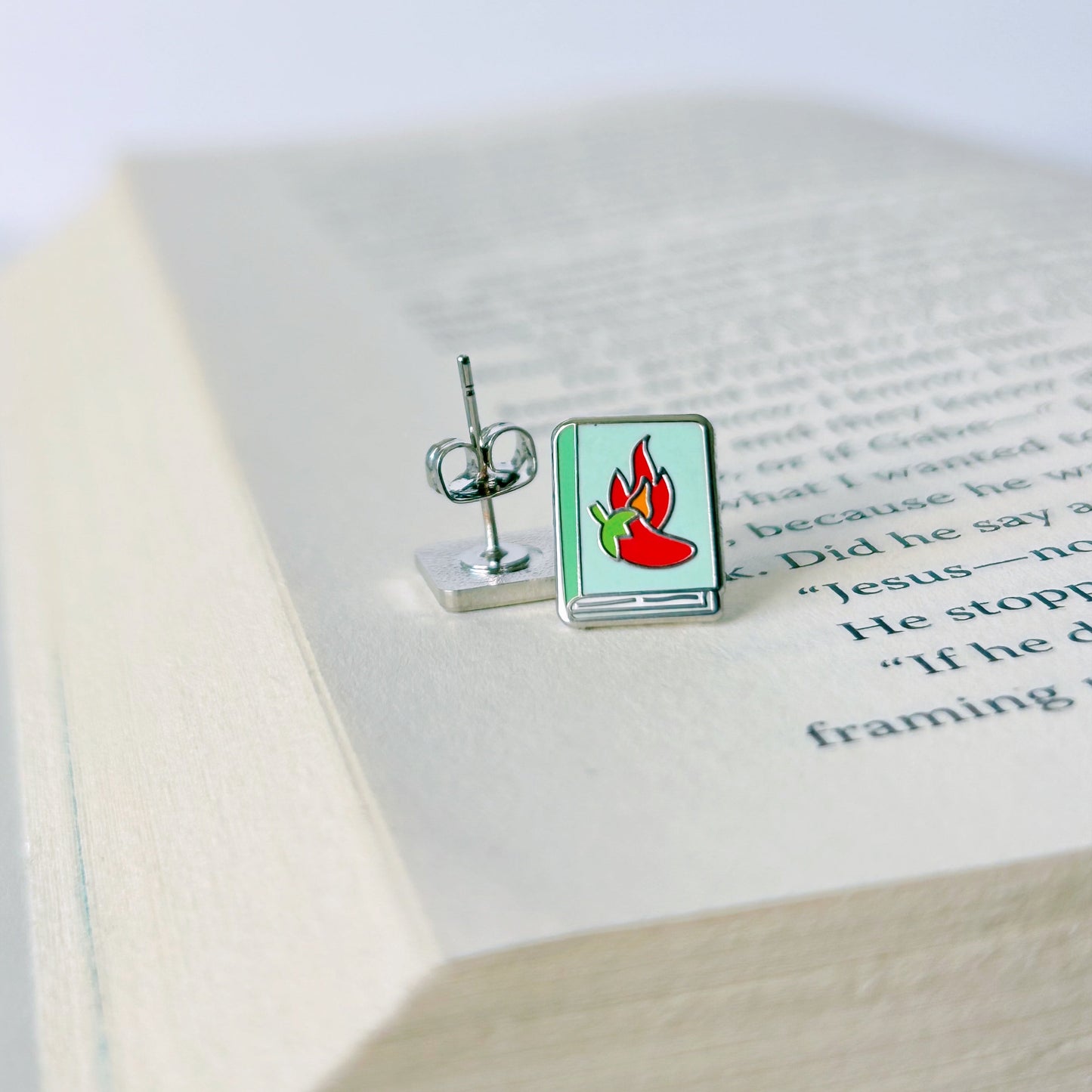 Pair of earrings with a flame design on an open book