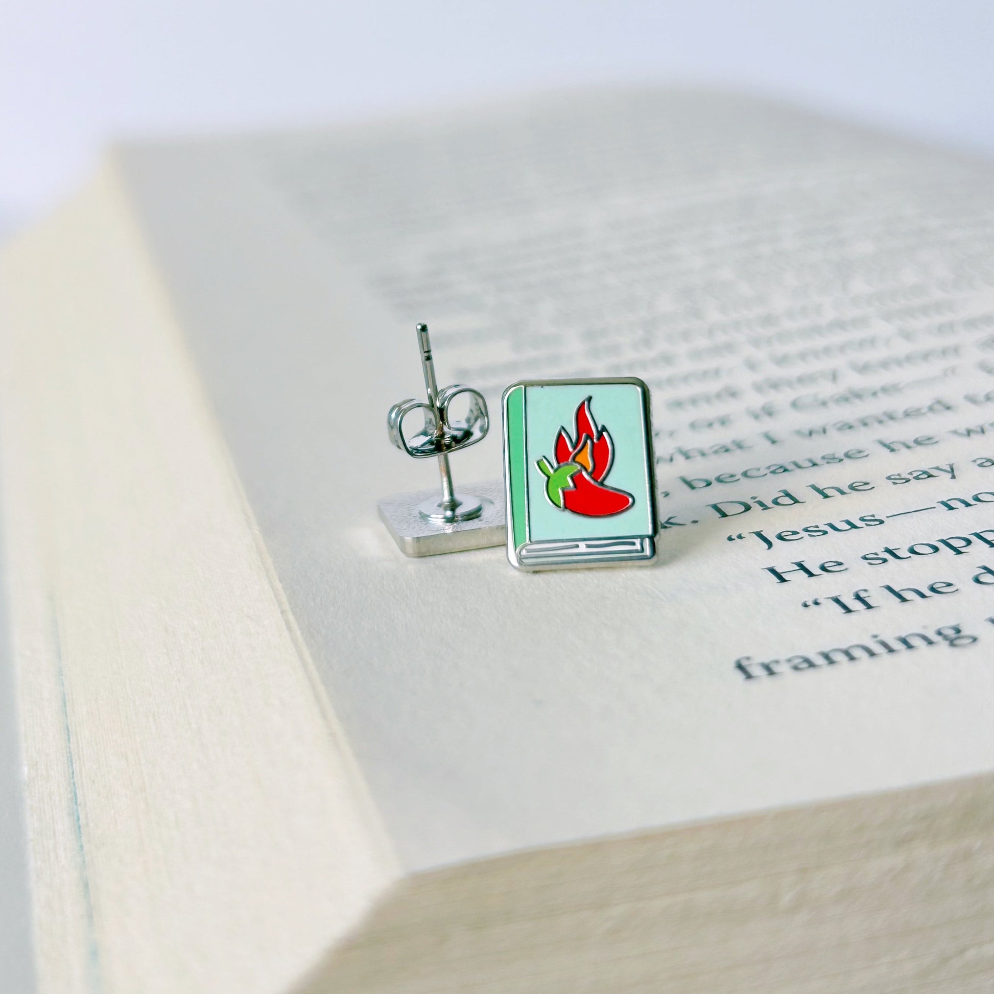 Pair of earrings with a flame design on an open book