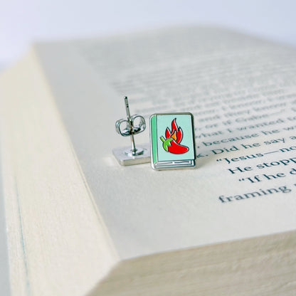 Pair of earrings with a flame design on an open book